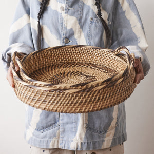 Person holding a stack of handwoven trays