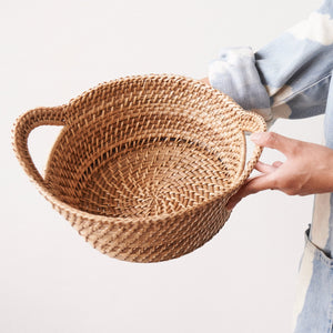 Person holding a handwoven rattan basket